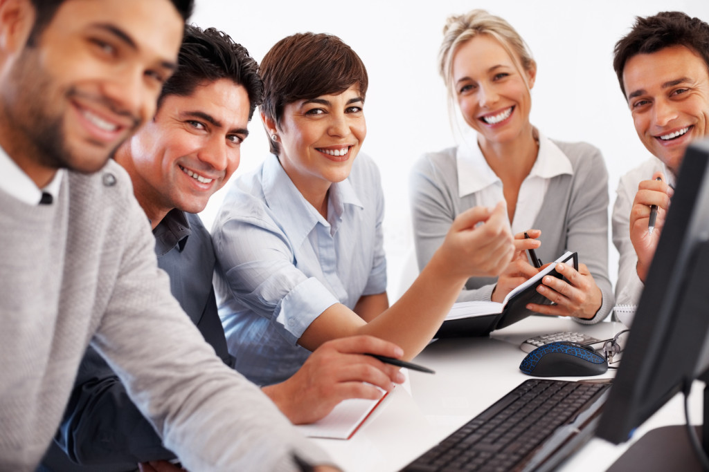 Happy female leader in center with team during business meeting