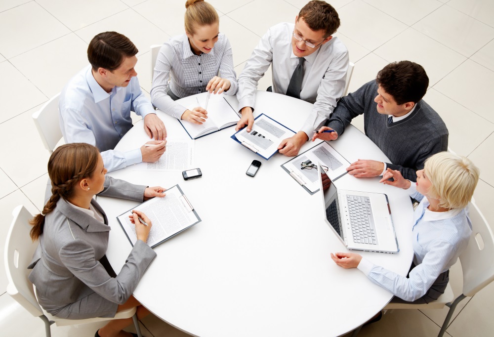 Image of company of successful partners discussing business plan at meeting